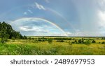 Double rainbow on a panoramic view of a river valley in the countryside. Picturesque landscape with green grass and blooming meadow herbs on a summer day. Natural landscape of nature in Ukraine
