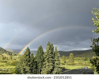 Double rainbow over dark clouds in mountain scape
