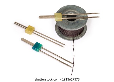 Double Sewing Machine Needles Different Size And Metal Bobbin With Black Threads Close-up On A White Background 
