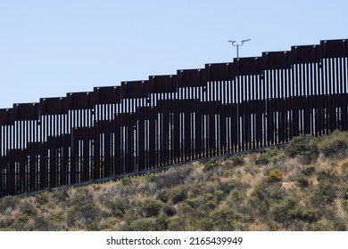 A double vertical border wall between the United States and Mexico, separating San Diego and Tijuana, viewed from the Border Field State Park in San Diego, California.