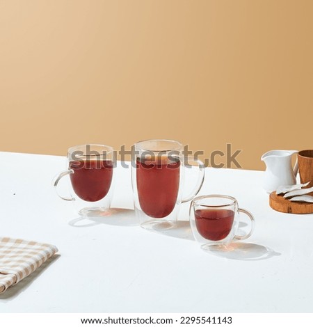 double wall translucent plastic glass with tea inside it on a white and cream background.