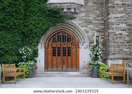 double wooden front door with leaded glass and ivy covered stone wall of  college building