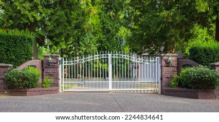 Double wrought-iron gate. Wrought iron gate and stone pillar. White wrought iron entrance gates to rural property. Nobody, street photo