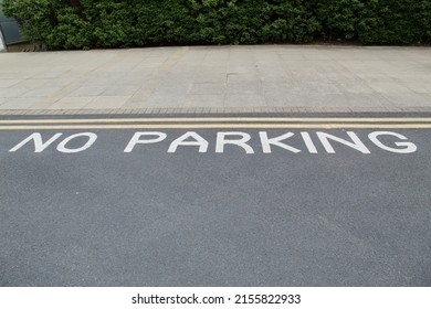 Double Yellow Lines Between the Pavement and the Road and No Parking Written on the Tarmac With White Road Paint