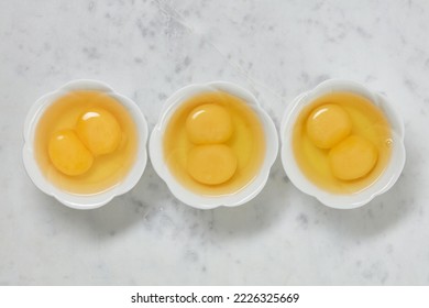 Double yolk eggs in a bowl on a white marble surface. Two yolks in one chicken egg. Identical twins. Double eggs. Flat lay
