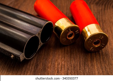 Double-barreled shotgun barrel and two red cartridges closeup