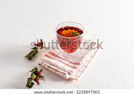 a double-bottomed glass cup with hot rosehip broth stands on a towel and a white table. prevention and treatment of avitominosis. increased immunity