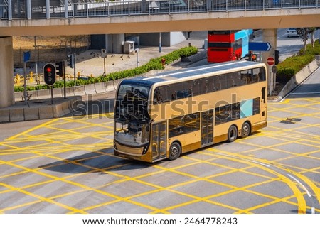 Double-decker city shuttle bus at an intersection with markings rides down the street, aerial view.