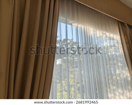 double-layered window curtains (curtains), consisting of a thick brown curtain layer on the outside and a thin white sheer curtain layer on the inside.