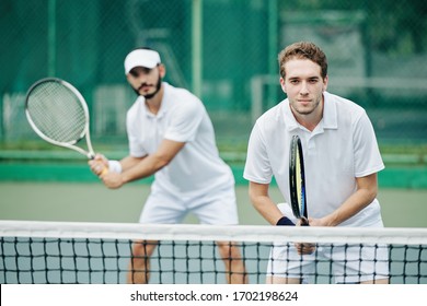 Doubles team of tennis players in white sportswear ready to hit the ball
