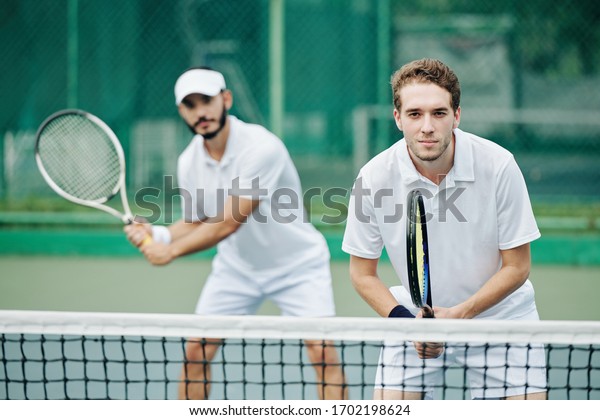 Doubles team of tennis players in white sportswear\
ready to hit the ball