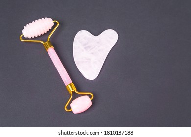 Double-sided Dermatology Roller Made Of Rose Quartz And Gua Sha Scraper For Rejuvenating And Wellness Massage Of Face, Neck And Decollete Area On Black Background, Top View, Copy Space