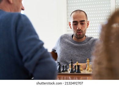 Doubt And Strategy Concept. Young Man Meditates About Next Move In Chess Game