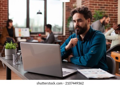 Doubtful pensive entrepreneur having uncertain think about marketing project analyzing company turnover on computer. Businessman working at business collaboration in startup office. Diverse team - Shutterstock ID 2107449362