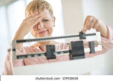 Doubtful woman adjusting weight scale - Shutterstock ID 159928418