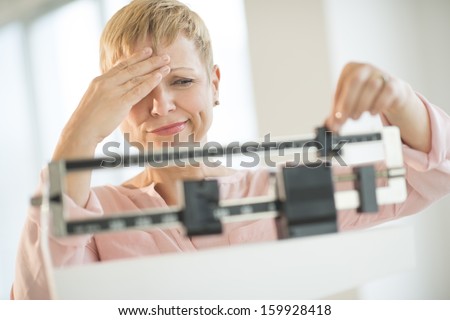 Doubtful woman adjusting weight scale