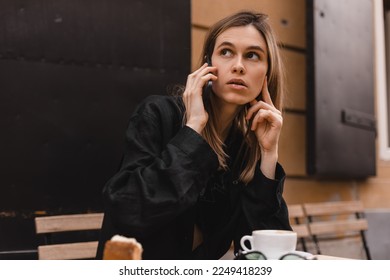 Doubtful young adult woman talking on cell phone making call looking away thinking of solution sitting in cafe, considering offer, making decision or feeling doubt. - Powered by Shutterstock