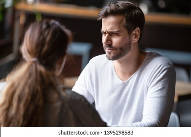 Doubting dissatisfied man looking at woman, bad first date concept, young couple sitting at table in cafe, talking, bad first impression, new acquaintance in public place, unpleasant conversation - Powered by Shutterstock