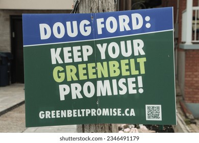 doug ford keep your greenbelt promise sign on wood post in front of residential homes, green blue white rectangle sign