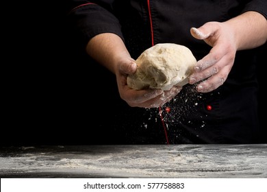 Dough in chef hand on a dark black background of wood. Baking bread, pizza, pasta. Recipe from chef cooks pizza. Italian home cooking. Horizontal photo with text area space for menu design  - Powered by Shutterstock