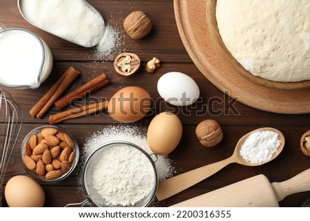 Dough and ingredients for pastries on wooden table, flat lay