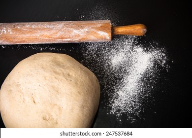 Dough, Rolling Pin And Flour On A Black Background.