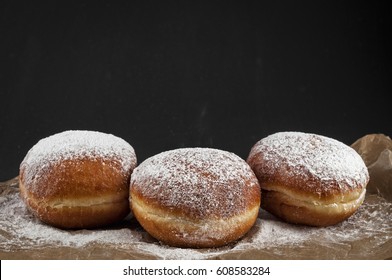 Doughnut is jam-packed with jelly filling and dusted in snowy powdered sugar. On a dark background