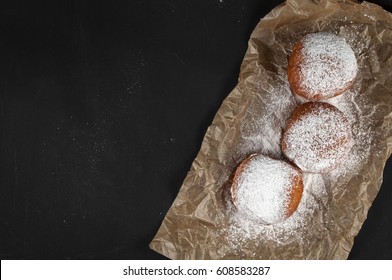 Doughnut is jam-packed with jelly filling and dusted in snowy powdered sugar. On a dark background