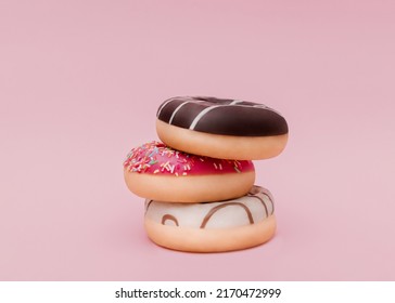 Doughnuts. Photo in minimal style. Mixed frosted sprinkled donuts on pink backdrop 