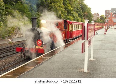 Douglas, Isle Of Man, UK - July 05, 2011: The Red Steam Locomotive With Train Of IMR Line In Puffs Of Vapour Prepares To Depart From The Platform Of Douglas Railway Terminal Station