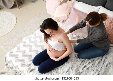 Doula massaging pregnant woman at home