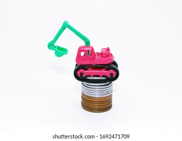 Dourados, MS, Brazil - April 1, 2020. Coins Of Various Values ​​below. Above, A Miniature Plastic Excavator, An Old Toy. Representing Construction Businesses. Ventures On White Background.