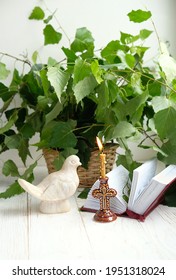 Dove figurine, church candle, bible book and birch leaves on wooden table. Dove - symbol of Holy Spirit. Holy Trinity Sunday. festive traditional composition for Pentecost day. concept of faith, God.