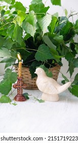 Dove figurine, church candle and birch leaves on wooden table. Dove - symbol of Holy Spirit. Holy Trinity Sunday. festive traditional composition for Pentecost day. concept of faith, God.