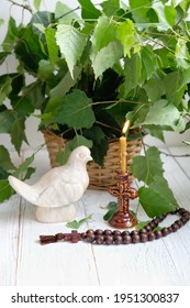 Dove figurine, church candle, rosary beads and birch leaves on wooden table. Dove - symbol of Holy Spirit. Holy Trinity Sunday. festive traditional composition for Pentecost day