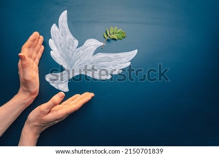 Dove of peace concept. Symbol of freedom and international day of peace. Hands let out chalk painted dove with olive branch