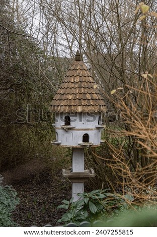 A dovecote shelter for birds and doves pigeons with multiple entrances and a pointed roof on a wooden post. Nesting sites man made by people to decorate and adorn gardens. Bird House, Handmade wooden.