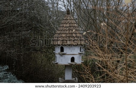 A dovecote shelter for birds and doves pigeons with multiple entrances and a pointed roof on a wooden post. Nesting sites man made by people to decorate and adorn gardens. Bird House, Handmade wooden.