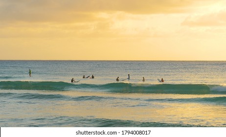 DOVER BEACH, BARBADOS, CARIBBEAN ISLANDS, DECEMBER 2019: Friends Surfing In Barbados Wait Together In Line Up At Golden Sunset. Longboarders Rest On Surfboards And Chat On A Sunny Summer Evening.