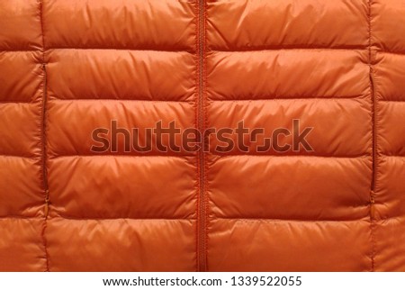 Down jacket fabric background, orange puffer jacket texture