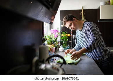 Down syndrome adult man standing indoors in kitchen at home, helping. - Shutterstock ID 1869078541