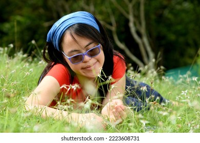 Down Syndrome, Adult Woman Resting On The Grass In The Summer Sun