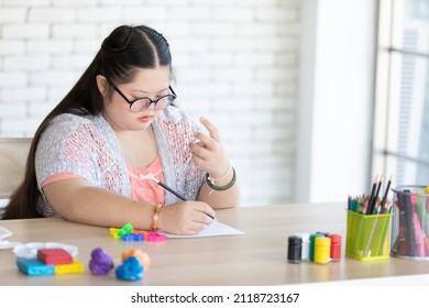 down syndrome girl writing and counting finger on paper