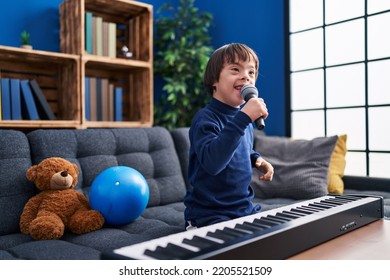 Down Syndrome Kid Singing Song Sitting On Sofa At Home