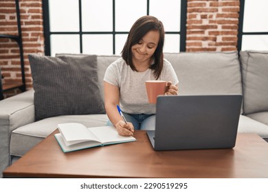 Down syndrome woman smiling confident working sitting on sofa at home