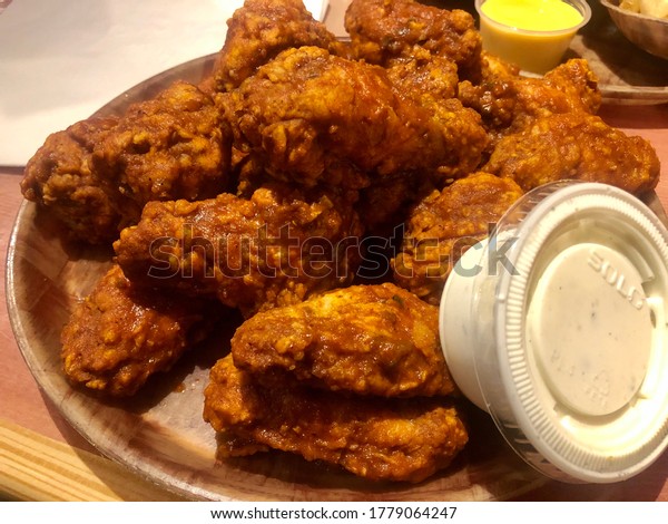 Downers Grove, IL / USA - 7/17/2020
: HOOTERS - Original Style Bone-In Wings with 9-1-1 sauce all over
them. Side of Bleu Cheese. Served on a wooden
platter.