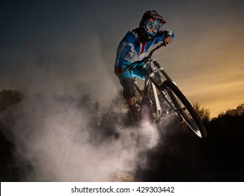 Downhill Cycling. Man Jump On A Mountain Bike With Dust. Extreme Sport.