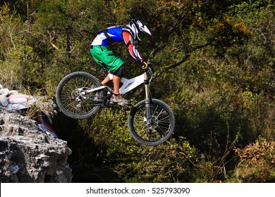 Downhill Mountain Biker With Green Shorts  Jumping From A Drop