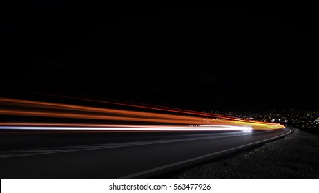 downhill red light trails with the city light in the background. - Shutterstock ID 563477926