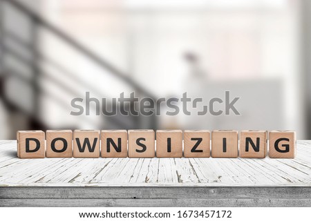 Downsizing message sign made of wood on a white desk in an office environment